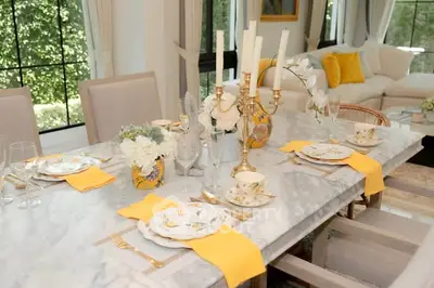 Elegant dining room with marble table, stylish decor, and large windows overlooking lush greenery.