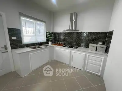 Modern kitchen with sleek black backsplash and stainless steel range hood