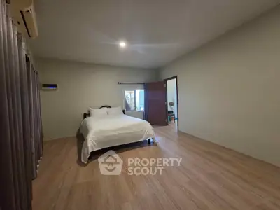 Spacious bedroom with wooden flooring and cozy ambiance