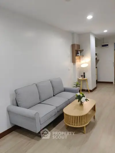 Modern living room with stylish gray sofa and wooden coffee table in a cozy apartment.