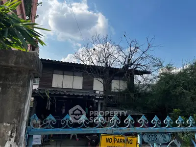 Charming rustic house with blue gate and lush greenery under a clear blue sky.