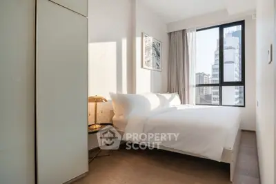Modern bedroom with large window and city view, featuring elegant decor and natural light.