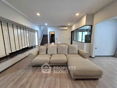Spacious modern living room with stylish beige sectional sofa and elegant wooden flooring.