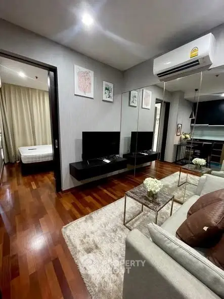 Modern living room with hardwood floors, cozy sofa, and wall-mounted TV in a stylish apartment.