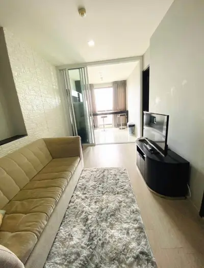 Modern living room with cozy sofa and TV, leading to a bright balcony view.