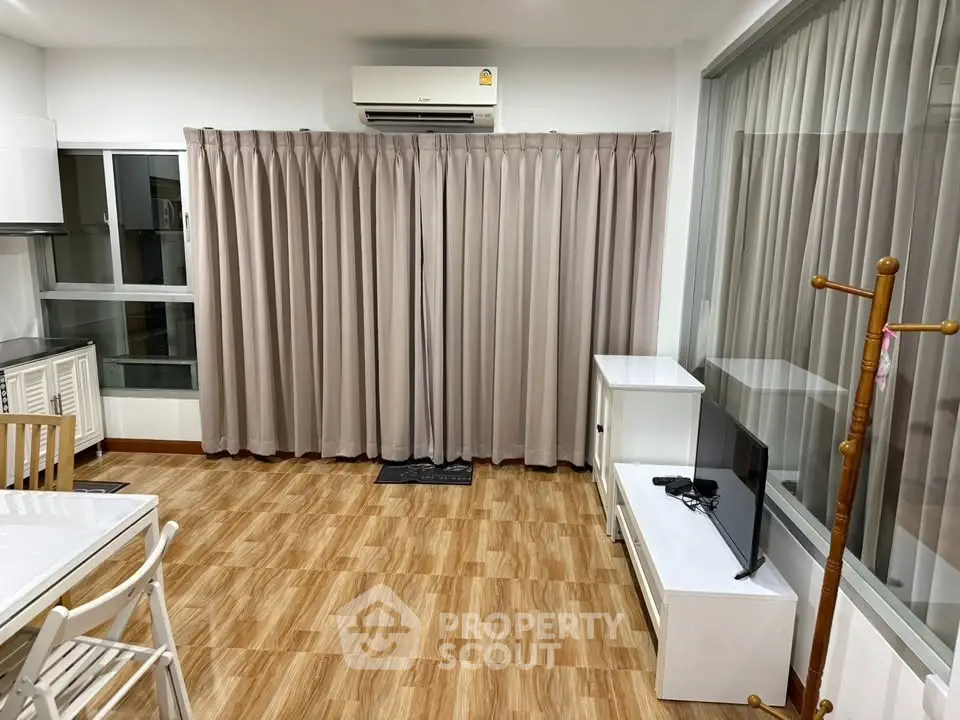 Modern living room with air conditioning and stylish curtains, featuring a compact TV setup and dining area.