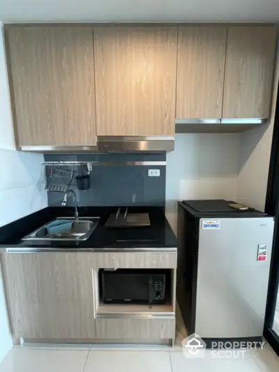 Modern compact kitchen with sleek wooden cabinets and stainless steel appliances.