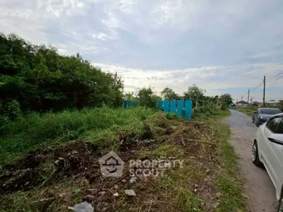 Vacant land plot with lush greenery and clear sky, ideal for development opportunities.