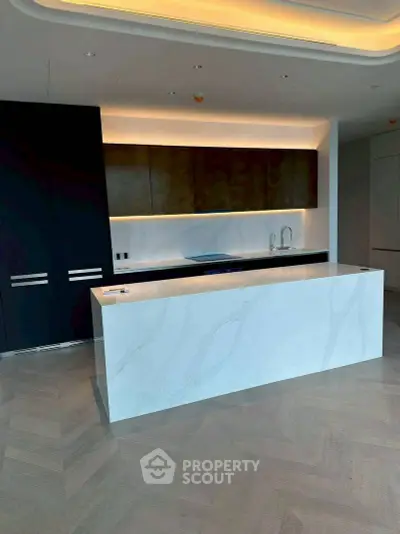 Modern kitchen with sleek island and ambient lighting, featuring a minimalist design and high-end finishes.