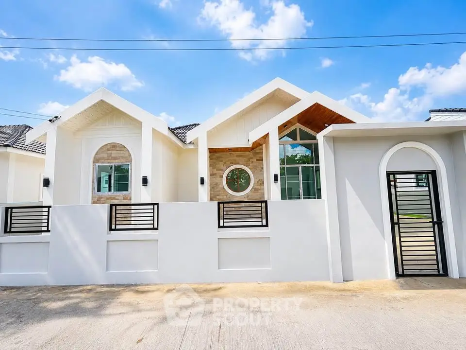 Charming modern bungalow with unique circular window and stylish facade under a clear blue sky.