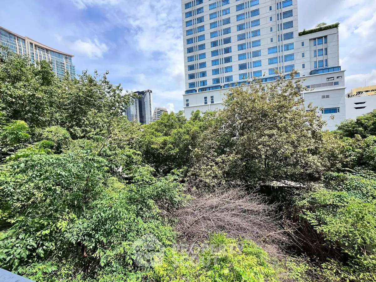Lush green garden view with modern high-rise buildings in the background.