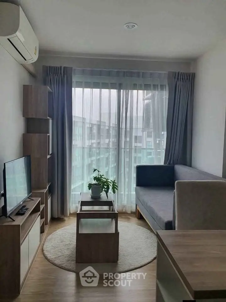 Modern living room with sleek furniture and large window offering natural light.