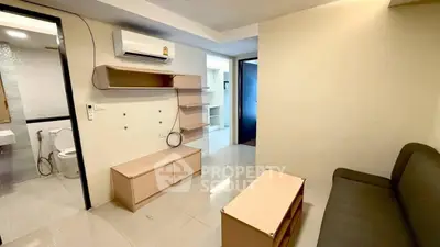 Modern living room with sleek furniture and air conditioning, adjacent to a bathroom.