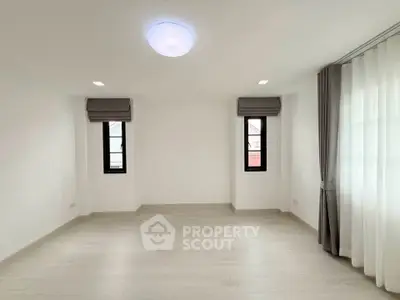 Spacious empty room with large windows and modern lighting, perfect for customization.
