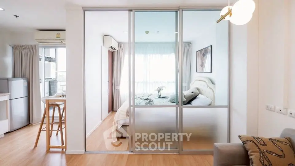 Modern apartment interior with glass partition separating bedroom and living area, featuring stylish decor.