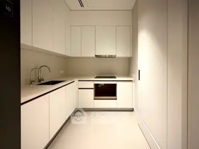 Modern minimalist kitchen with sleek white cabinetry and built-in oven, perfect for contemporary living.