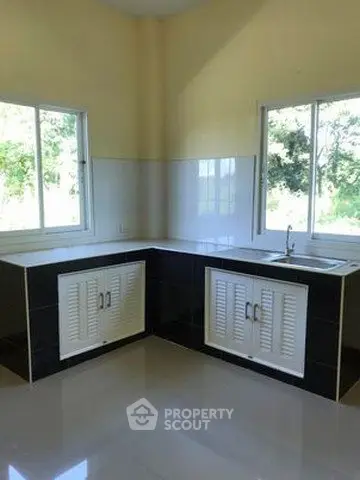 Modern kitchen with sleek black and white cabinetry and large windows for natural light.