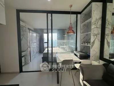 Modern apartment interior with marble accents and glass partition, featuring a cozy living area and study space.