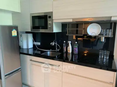 Modern kitchen with sleek appliances and black countertop in a stylish apartment.