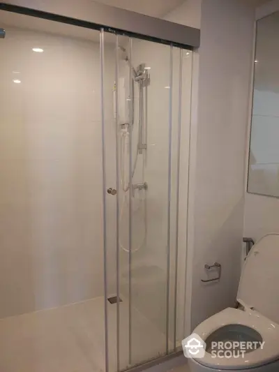 Modern bathroom with glass shower enclosure and toilet in sleek design.