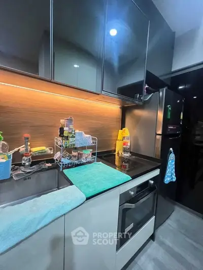 Modern kitchen with sleek cabinetry and built-in oven, featuring under-cabinet lighting and stainless steel appliances.