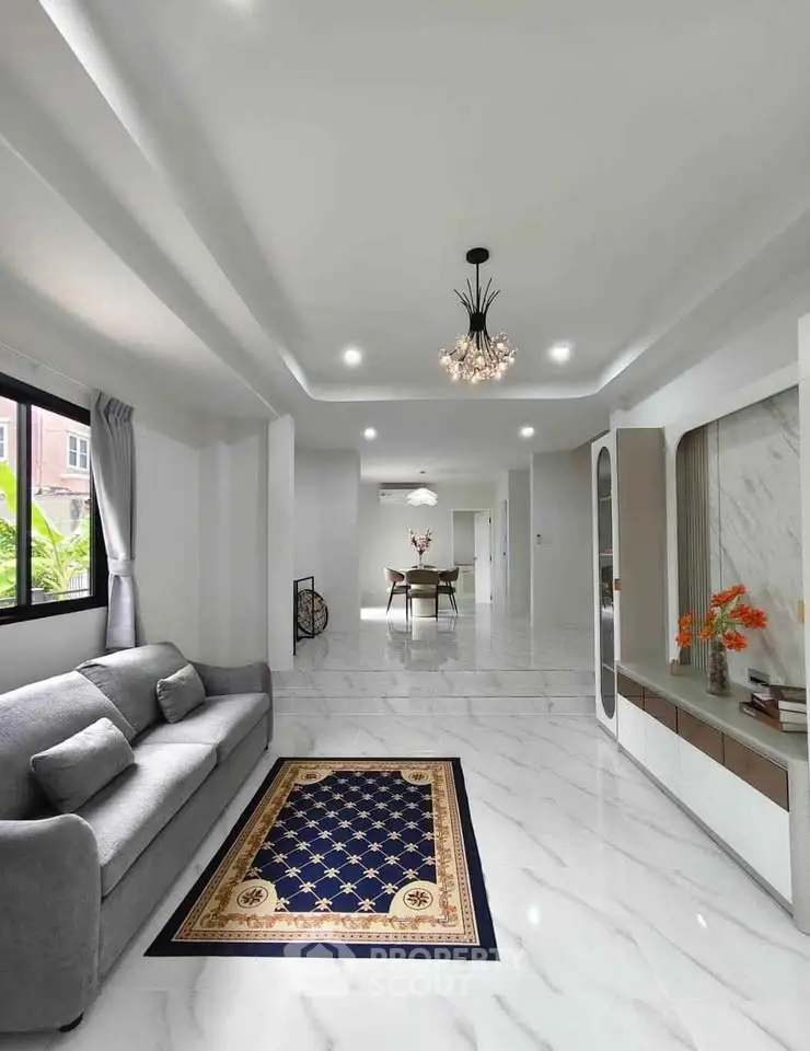 Spacious modern living room with elegant decor and marble flooring, featuring a cozy gray sofa and stylish lighting.