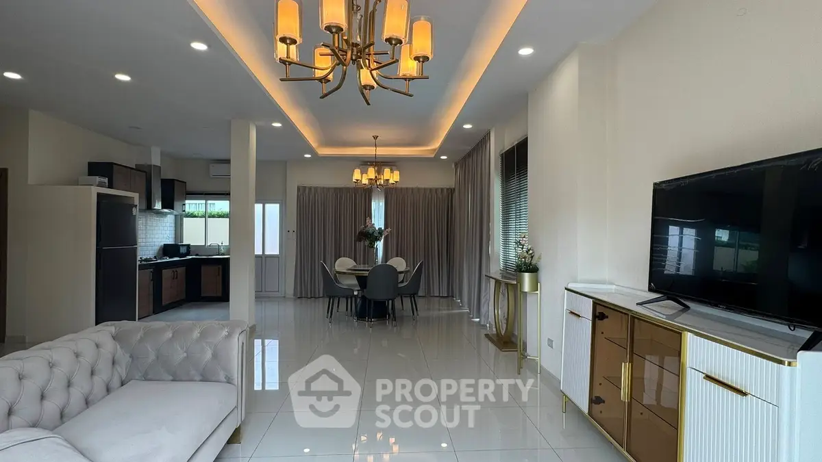 Spacious modern living room with elegant chandelier and open kitchen layout, perfect for entertaining.