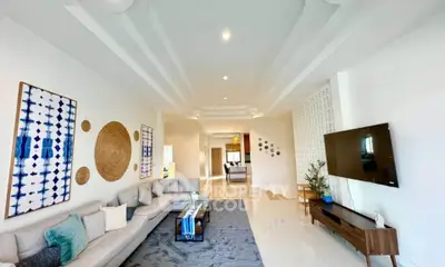 Spacious modern living room with elegant decor and large wall-mounted TV, perfect for relaxation.