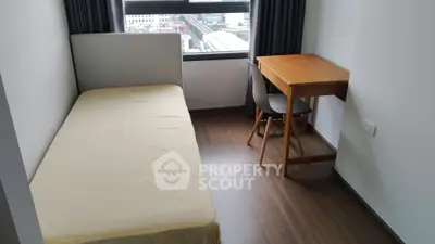 Cozy bedroom with single bed and study desk, featuring a city view from the window.