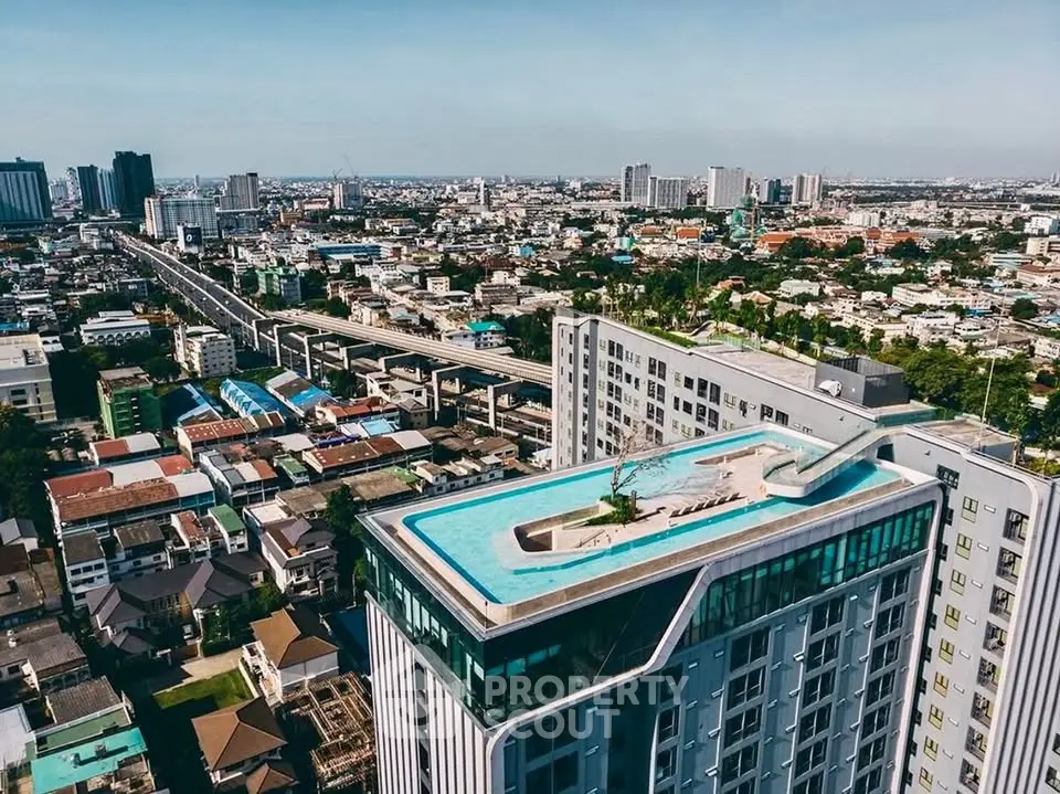 Stunning aerial view of modern high-rise building with rooftop pool and panoramic cityscape.