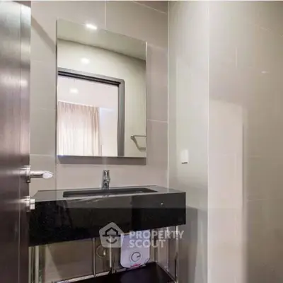 Modern bathroom with sleek black countertop and large mirror in a stylish apartment.
