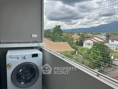 Balcony with washing machine and scenic view of suburban homes and mountains.