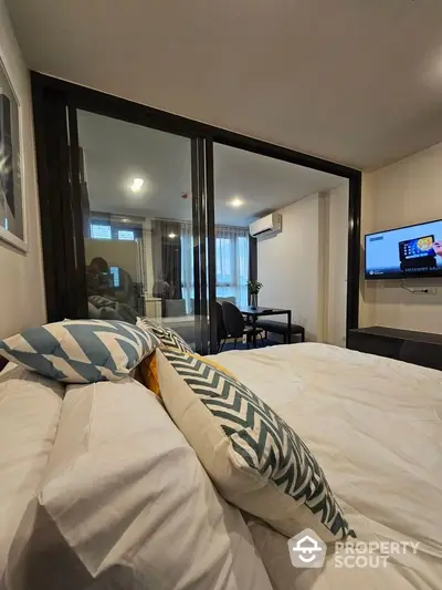 Modern bedroom with stylish decor and sliding glass doors leading to a cozy study area.