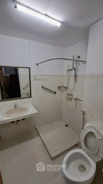 Accessible bathroom with shower, toilet, and safety bars in modern apartment.