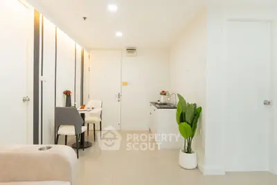 Modern open-layout living space with dining area and compact kitchen, featuring sleek design and neutral tones.