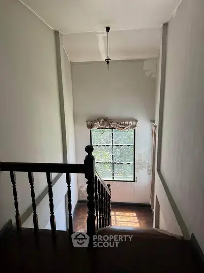 Charming staircase with natural light and wooden railing in cozy home interior.