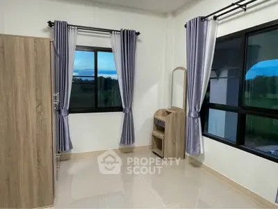 Spacious bedroom with large windows and modern furniture, offering serene views.