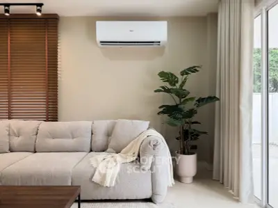 Modern living room with cozy sofa, air conditioning, and large window for natural light.