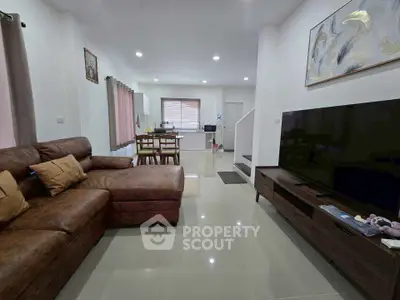 Spacious modern living room with large TV and stylish furniture, perfect for family gatherings.