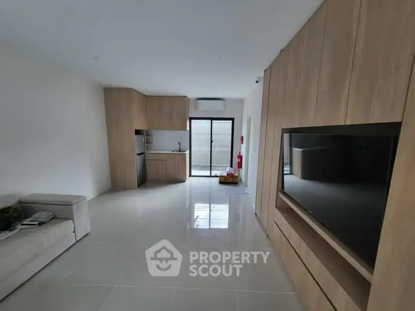 Modern open-plan living room with sleek kitchen and built-in TV unit
