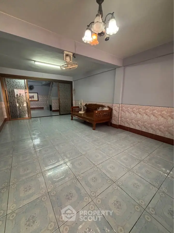 Spacious tiled living area with vintage wooden furniture and decorative lighting.