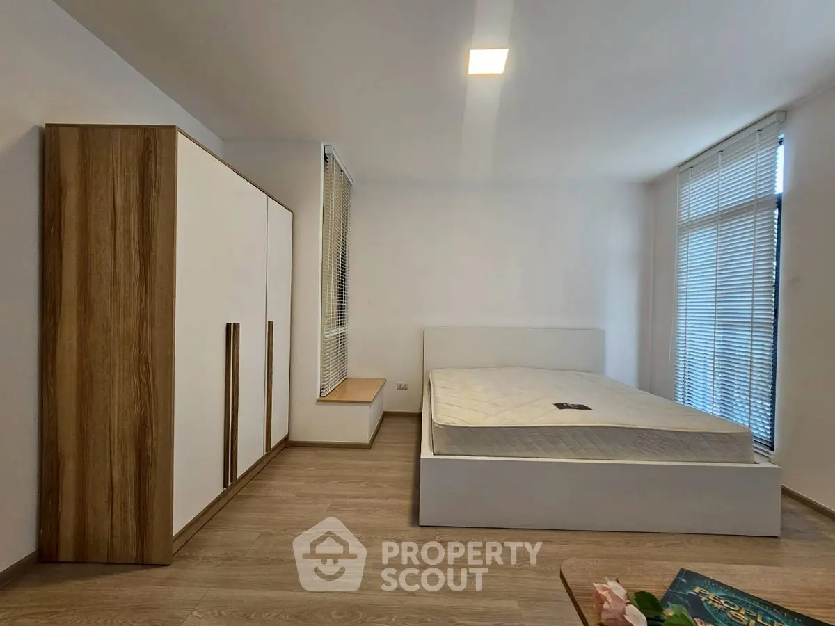 Spacious bedroom with modern minimalist design and large windows for natural light.