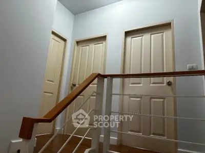Modern interior hallway with wooden railing and three doors