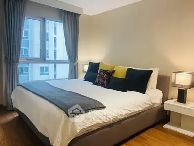 Modern bedroom with large window and stylish decor in urban apartment.