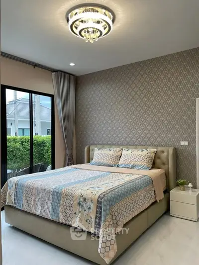 Luxurious bedroom with elegant decor and large window offering garden view, featuring a stylish chandelier.