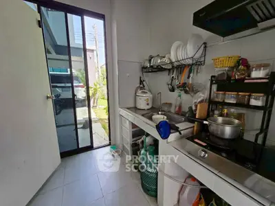 Compact kitchen with modern appliances and outdoor access, featuring a gas stove and ample storage space.