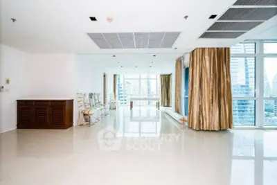 Spacious living room with large windows and city view in modern apartment.
