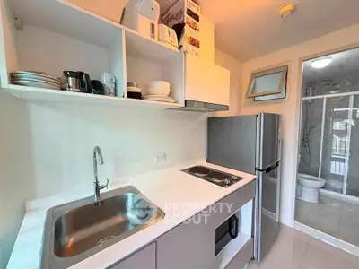 Modern kitchen with sleek appliances and adjacent bathroom in compact apartment.