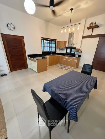 Modern kitchen with open layout and dining area, featuring sleek cabinetry and stylish lighting.