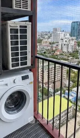 High-rise balcony with washing machine and cityscape view, perfect for urban living.